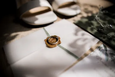 Wedding invitations with wedding shoes next to them, and a wax stamp