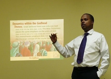 man in blue denim top standing under tree leaf