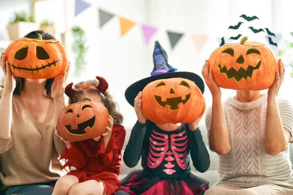 Children holding Halloween pumpkin puppets at a party