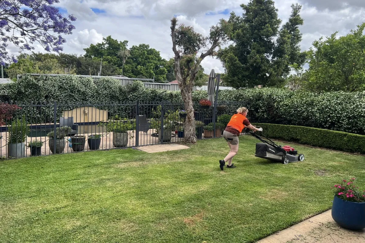Gardener mowing a large residential backyard lawn