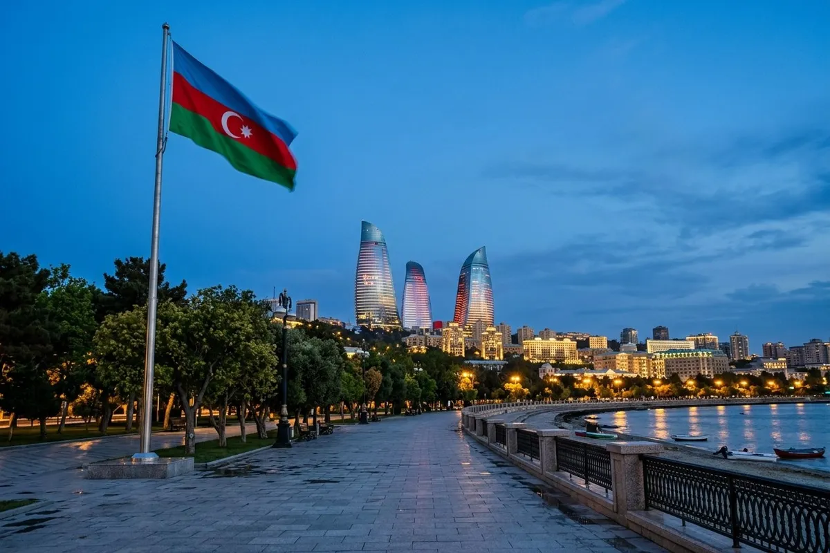 Caspian waterfront promenade at dusk with modern towers reflected in still water