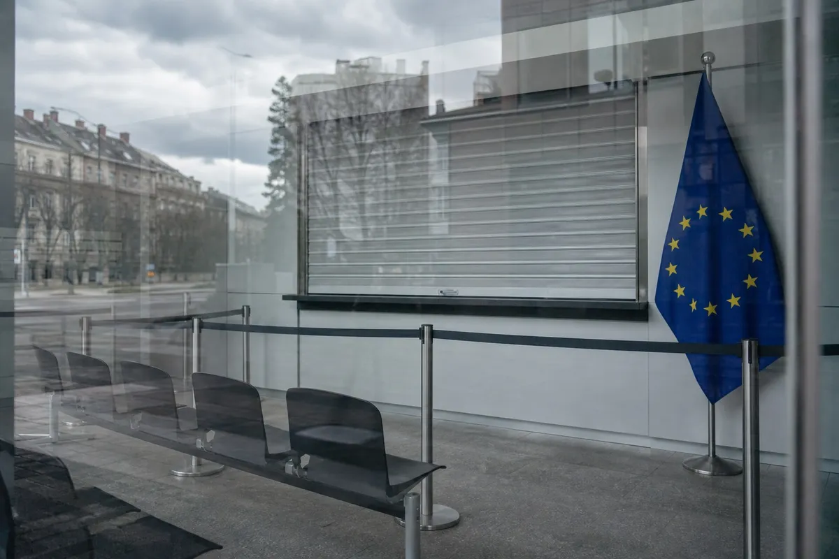 Empty consular waiting room with a single closed service window and rows of vacant chairs