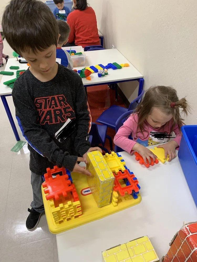 Boy and girl are building a structure with plastic building pieces