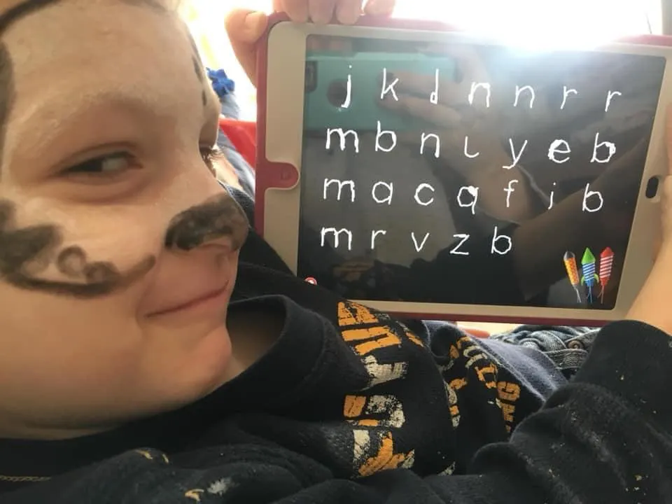 Boy showing his letter tracing work on the iPad