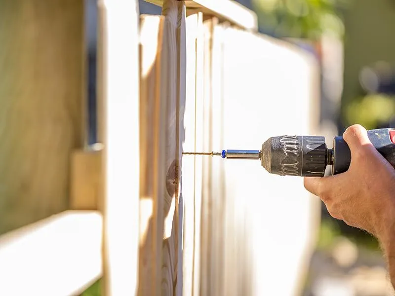 an expert contractor drilling a fence