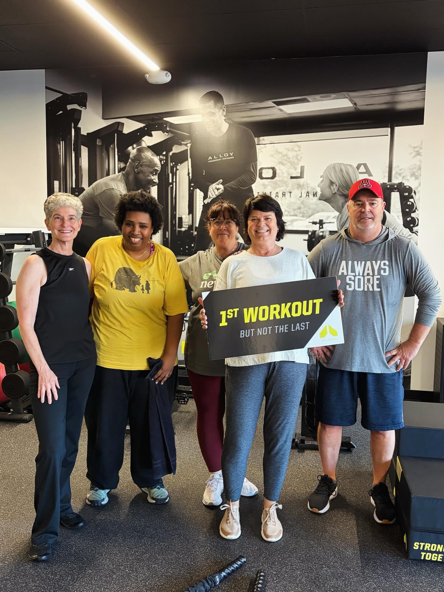 A group of clients smiling and posing in a photo frame after a small group personal training session at Alloy Personal Training, showcasing the community atmosphere and support during their fitness journey.