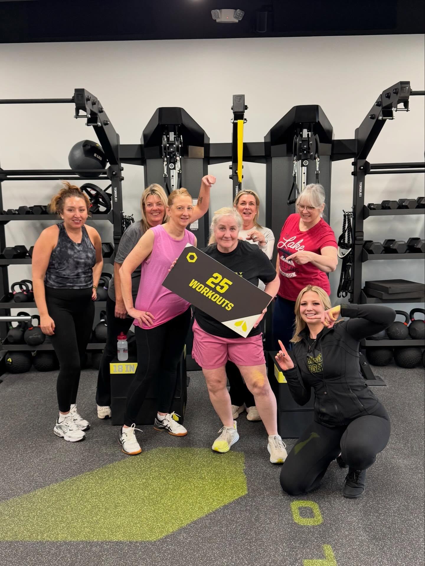 Group of women in small group personal training session at Alloy Personal Training Geneva celebrating 25 workouts in a strength training studio with kettlebells and functional fitness equipment in Geneva IL