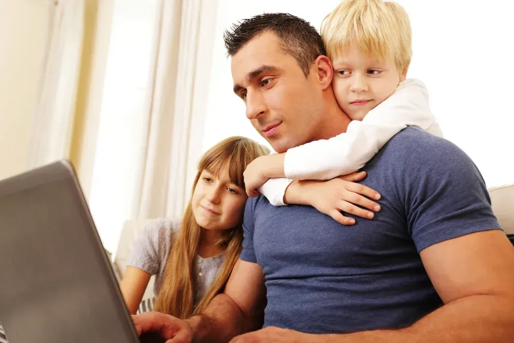 https://48546152.fs1.hubspotusercontent-na1.net/hubfs/48546152/Father%20with%20children%20working%20on%20laptop%20computer%20at%20home.jpeg