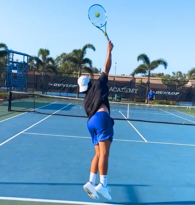 Jugador de tenis joven ejecutando saque profesional en academia de alto rendimiento en Katy Texas - Zenniq Academy