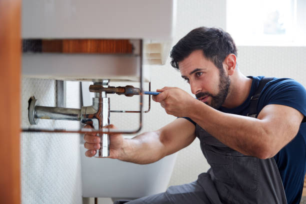 Plumber fixing pipework under a bathroom sink