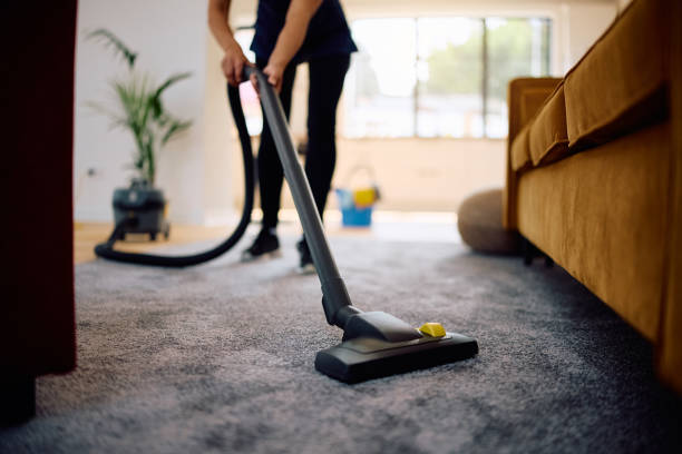Cleaner vacuuming a rug in a living room