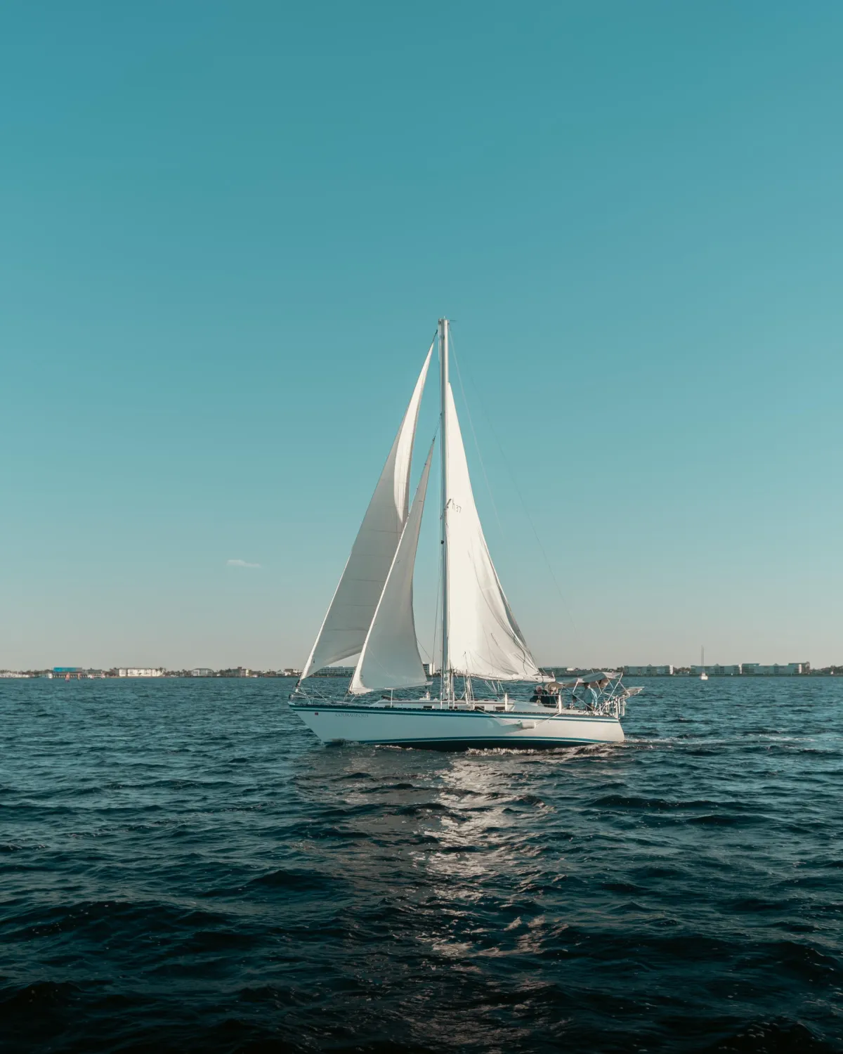 Sailing yacht on calm waters under a clear blue sky, representing Punta Gorda Adventures' sailing yacht charters.