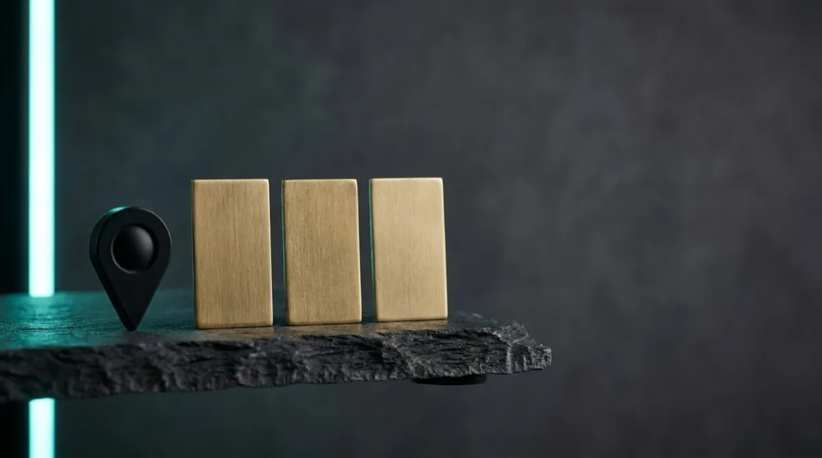 Three blank brushed brass name plates and a black map pin on a dark slate ledge, lit with a teal edge light.