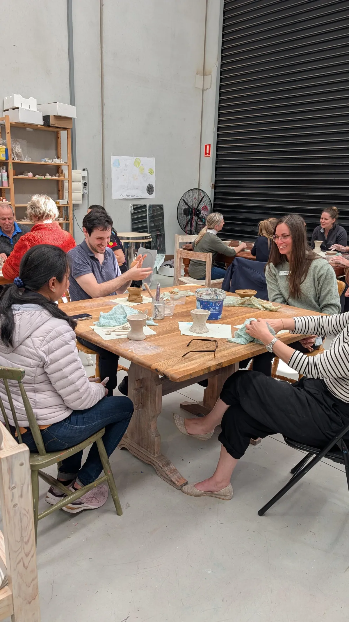 A bright lifestyle scene showing a single parent’s hands arranging colorful craft supplies on a table, natural daylight from a nearby window, candid warm mood, photorealistic editorial style, family-friendly atmosphere.