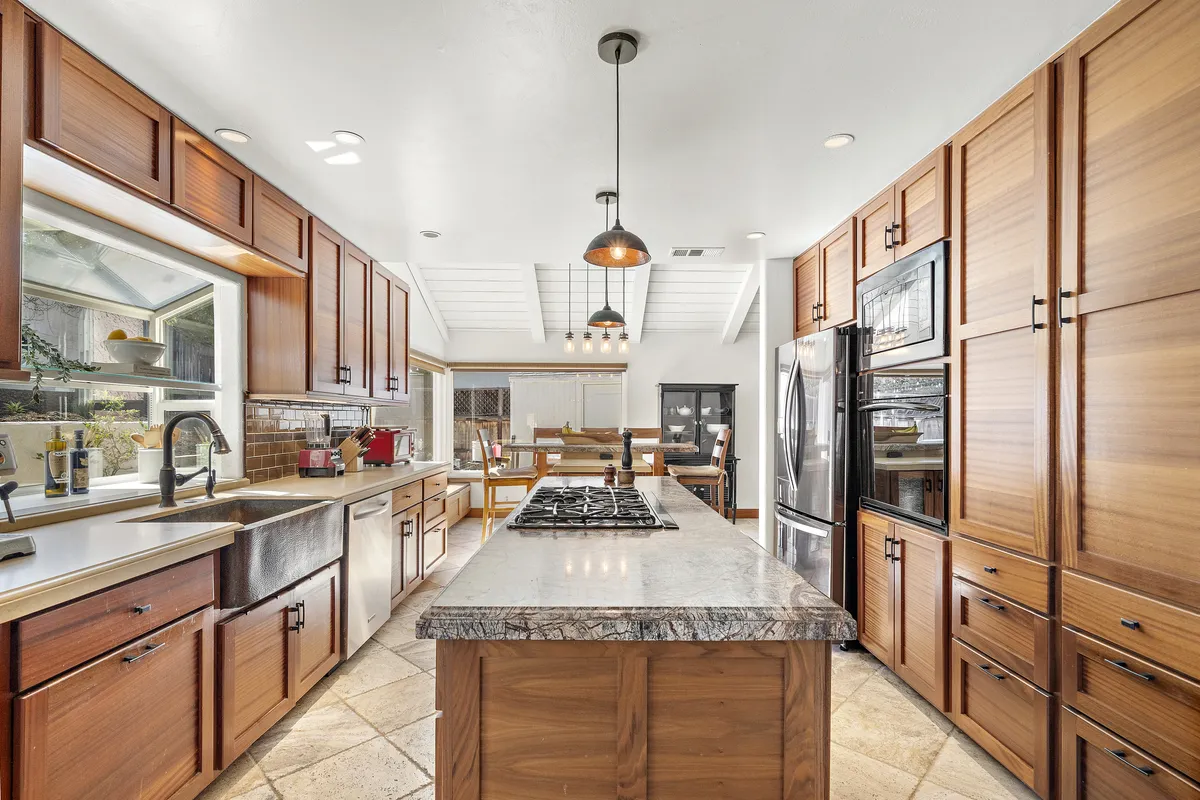 Kitchen at 25532 Leeward Drive with custom Sapele wood cabinetry, stone countertops and a copper farmhouse sink.