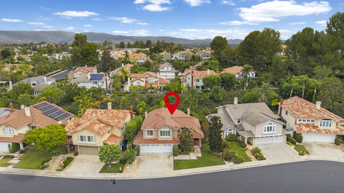 Aerial view of 22232 Hazel Crest marked with a red pin, with surrounding homes, mature trees, and distant hills.