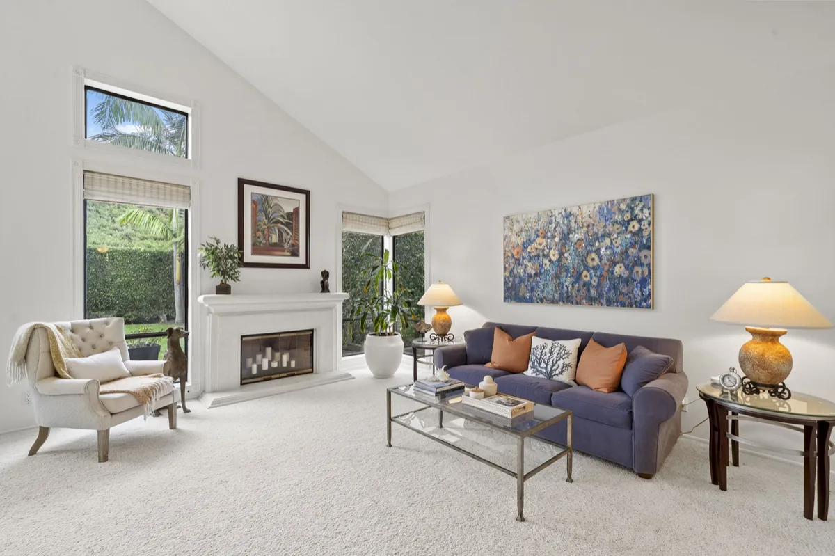  Living room with two-story ceilings, a fireplace, tall windows, and a blue sofa.