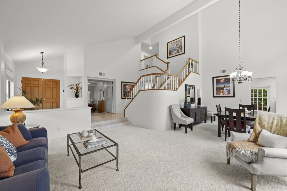 Main living area with two-story ceilings, an office nook beneath the staircase, and wood stair railings.