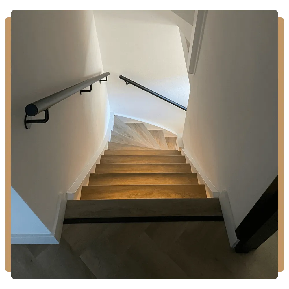 a hallway with a wooden banister and a painting on the wall