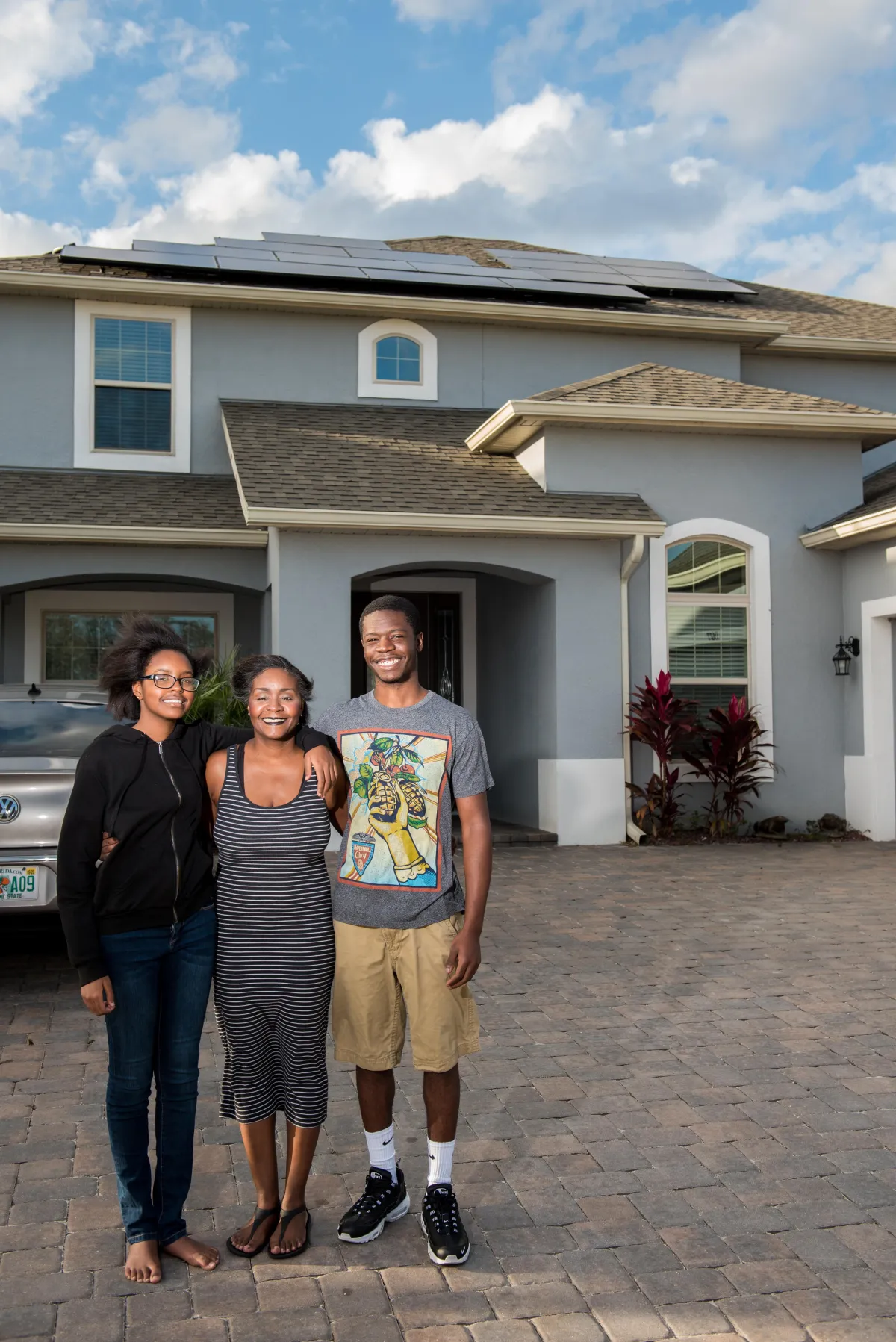 A joyful family stands proudly in front of their home, showcasing their brand new solar panels glistening under the sun. With beaming smiles, they embrace the benefits of solar power and their commitment to a sustainable future. The recently installed solar panels symbolize their shift towards clean energy, reducing their carbon footprint while enjoying energy savings. Witness the happiness and eco-consciousness of this family as they harness the power of the sun with their newly installed solar panels.