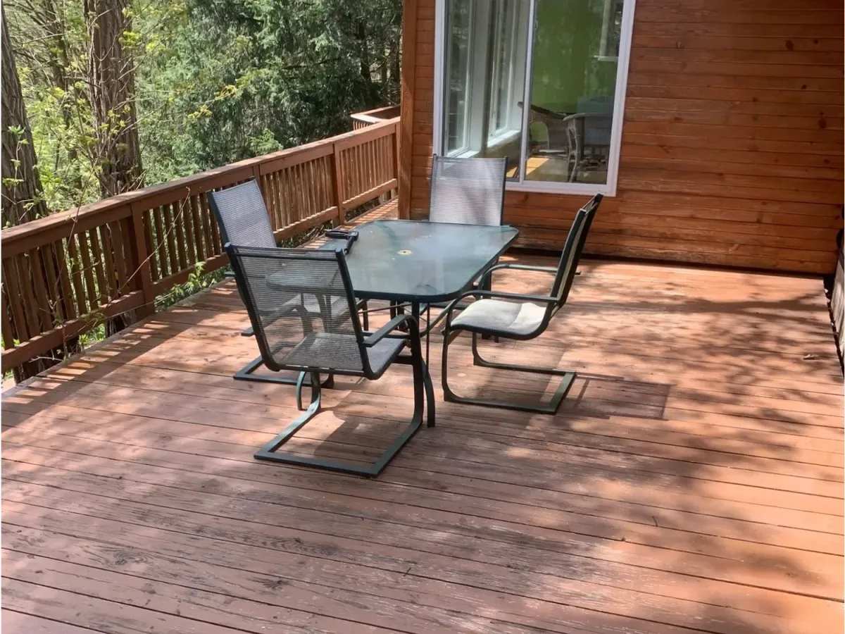 A wooden deck with a table and chairs in the middle looks clean, reinvigorated, and pristine after a deck power wash.