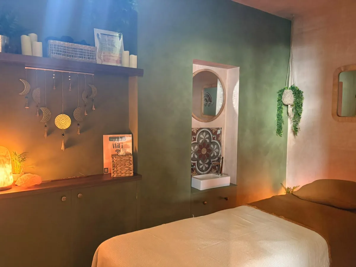 Fully clothed client lying on a massage table with only the therapist's hand visible, gently placed over the client's body; therapist not visible except for the hand.