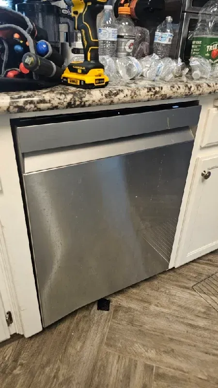 An experienced appliance repair tech replacing a faulty circulation pump motor inside a built-in kitchen dishwasher in Modesto, CA near the McHenry Avenue corridor.