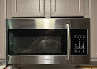 A professional appliance repair technician working safely on the electronic housing of an open microwave oven unit in Modesto, CA near the McHenry Avenue retail corridor.