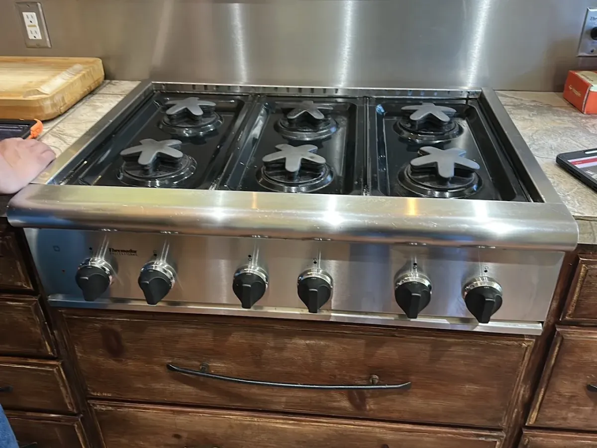 A local appliance technician using a specialized tool to check the internal heating components of an open oven cavity in Modesto, CA near the McHenry Avenue corridor.