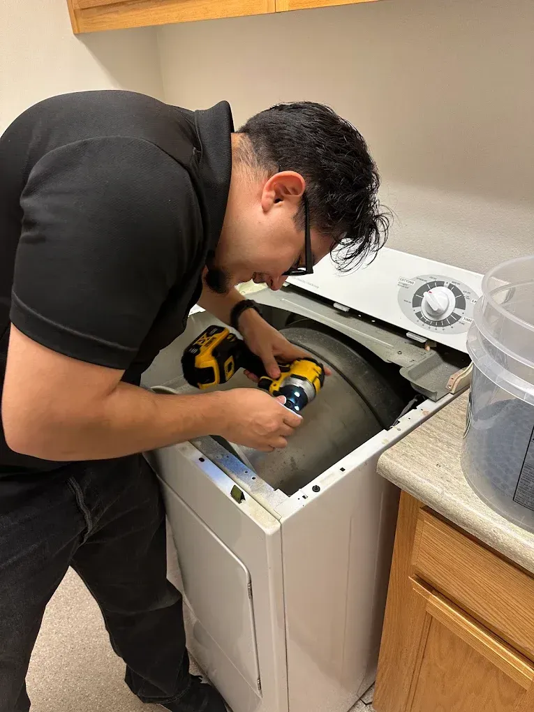 A professional laundry appliance technician repairing the internal door seal and control panels of a front-load washing machine unit in Modesto, CA near the North Beyer Park community.