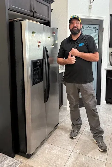 A factory-certified appliance repair service technician wearing a professional company uniform while inspecting the mechanical components of a home unit in Modesto, CA near the Sherwood Forest neighborhood.