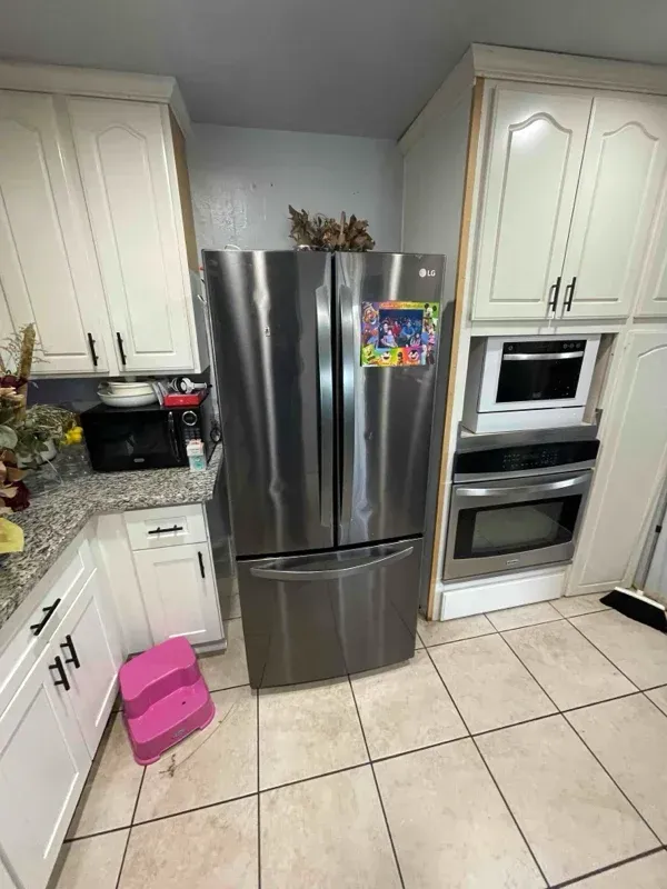 A certified appliance technician cleaning internal condenser coils and checking power draw metrics to optimize energy efficiency on a major home unit in Merced, CA near the UC Merced campus area.
