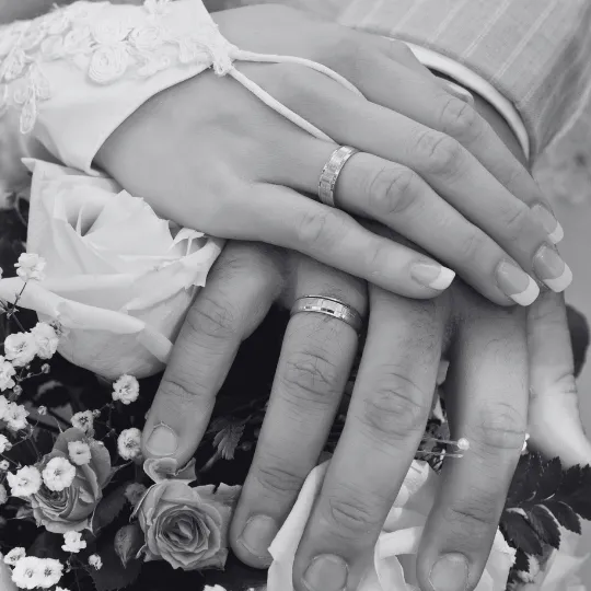 Bride & Grooms hands with a bouquet & wedding rings. 