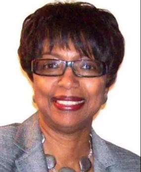 Headshot of Dr. Willi  G. Woods. She wears a grey blazer, a stone-beaded necklace and glasses.