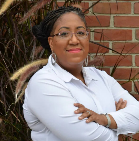 Headshot of Dr. Willi  G. Woods. She wears a grey blazer, a stone-beaded necklace and glasses.