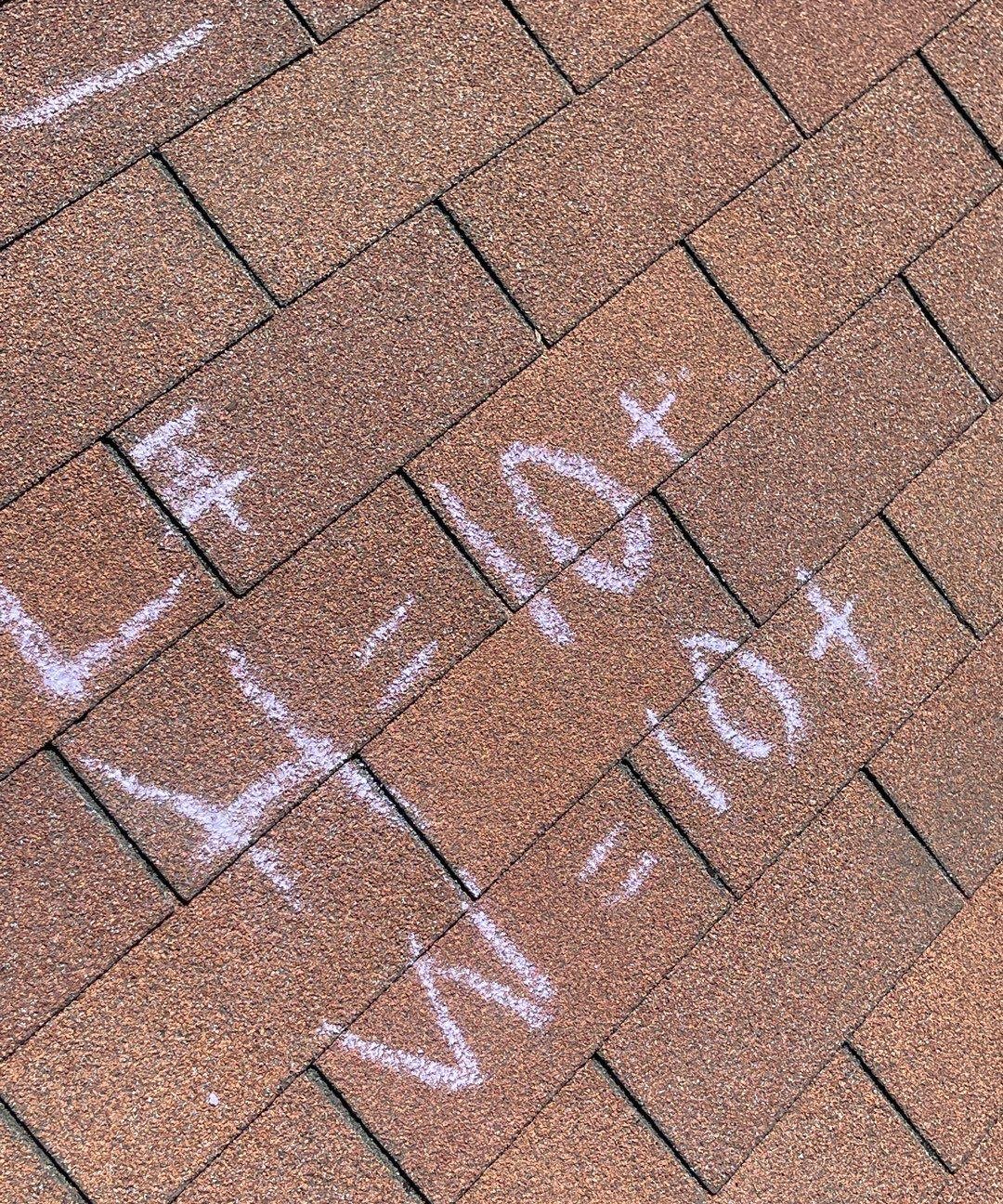 Brown asphalt shingles with chalk notes reading H=10+ and W=10+ written during a roof inspection