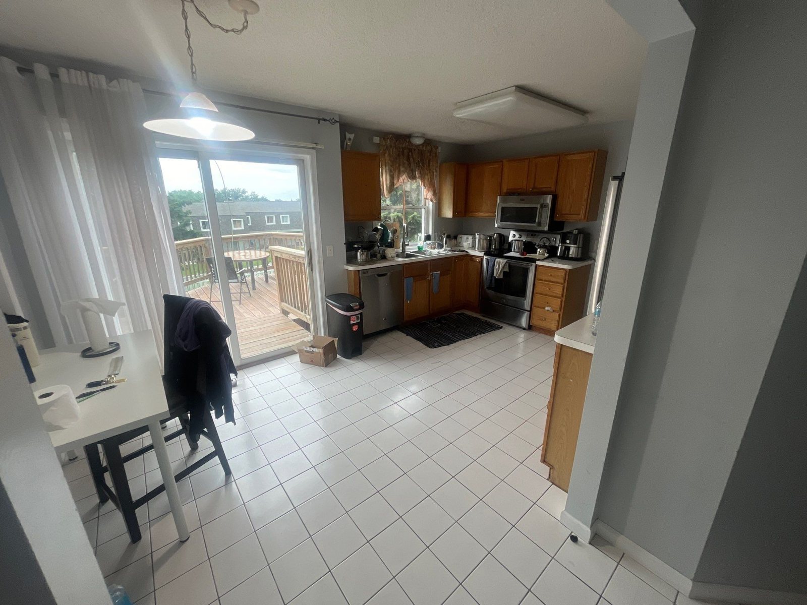 Kitchen with oak cabinets, white tile floor, and a patio door, photographed before a remodel