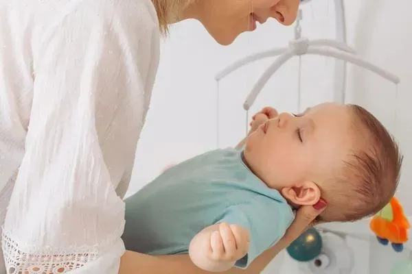 mum putting baby into cot to sleep