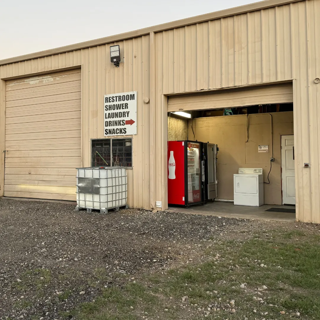 Row of premium rent-to-own portable buildings, utility sheds, and cabins staged on gravel lot at Location 2