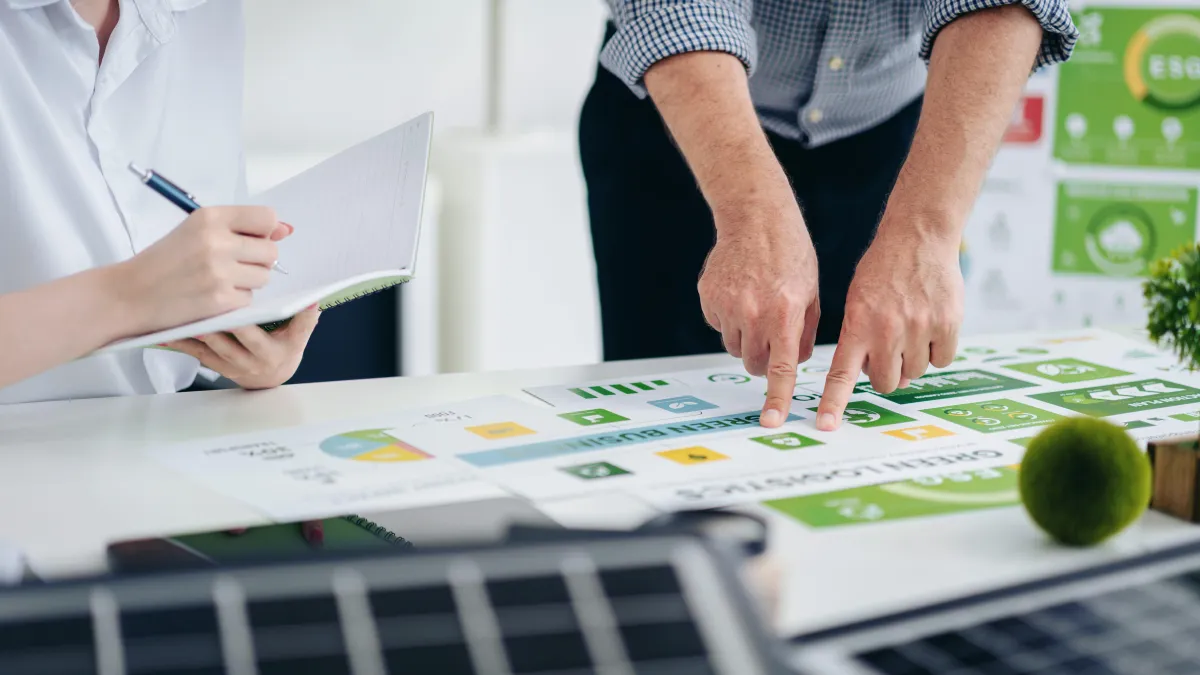 Man and woman lookin at coloured pie chart just printed on a printer for net zero cosultatio