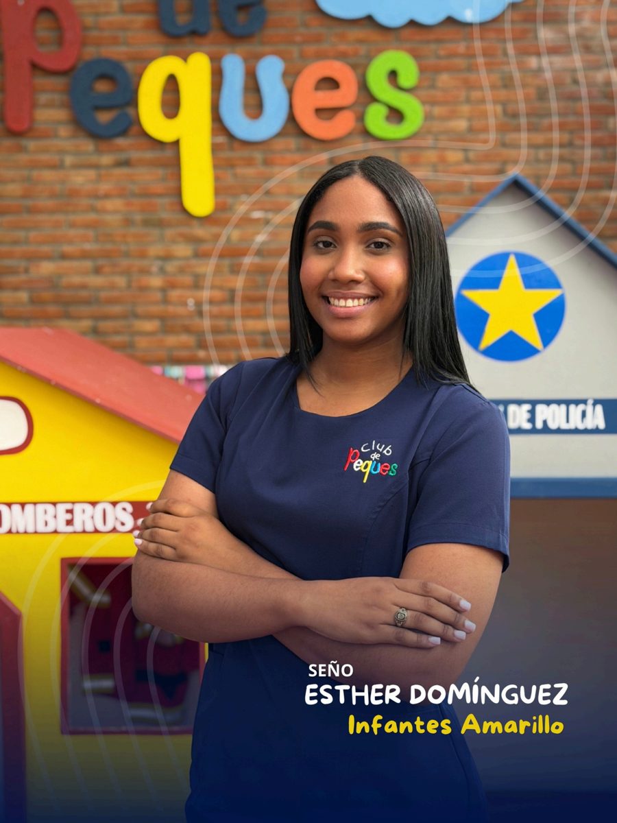 Waist-up portrait of Seño Esther Domínguez smiling, wearing a navy polo, in front of a colorful 'Peques' sign.