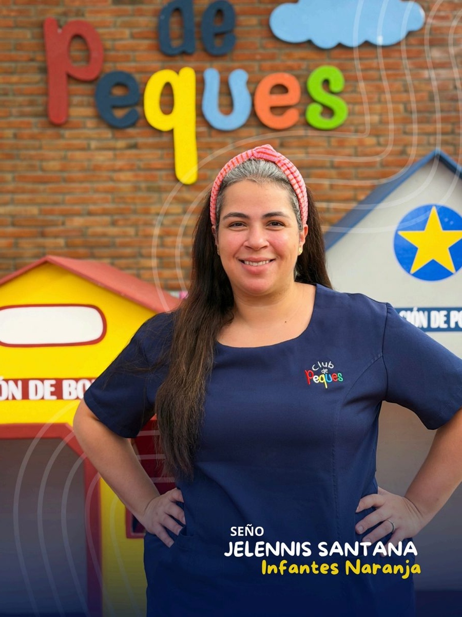 Waist-up portrait of Seño Jelennis Santana with crossed arms, wearing a navy polo, in front of a colorful 'Peques' sign.