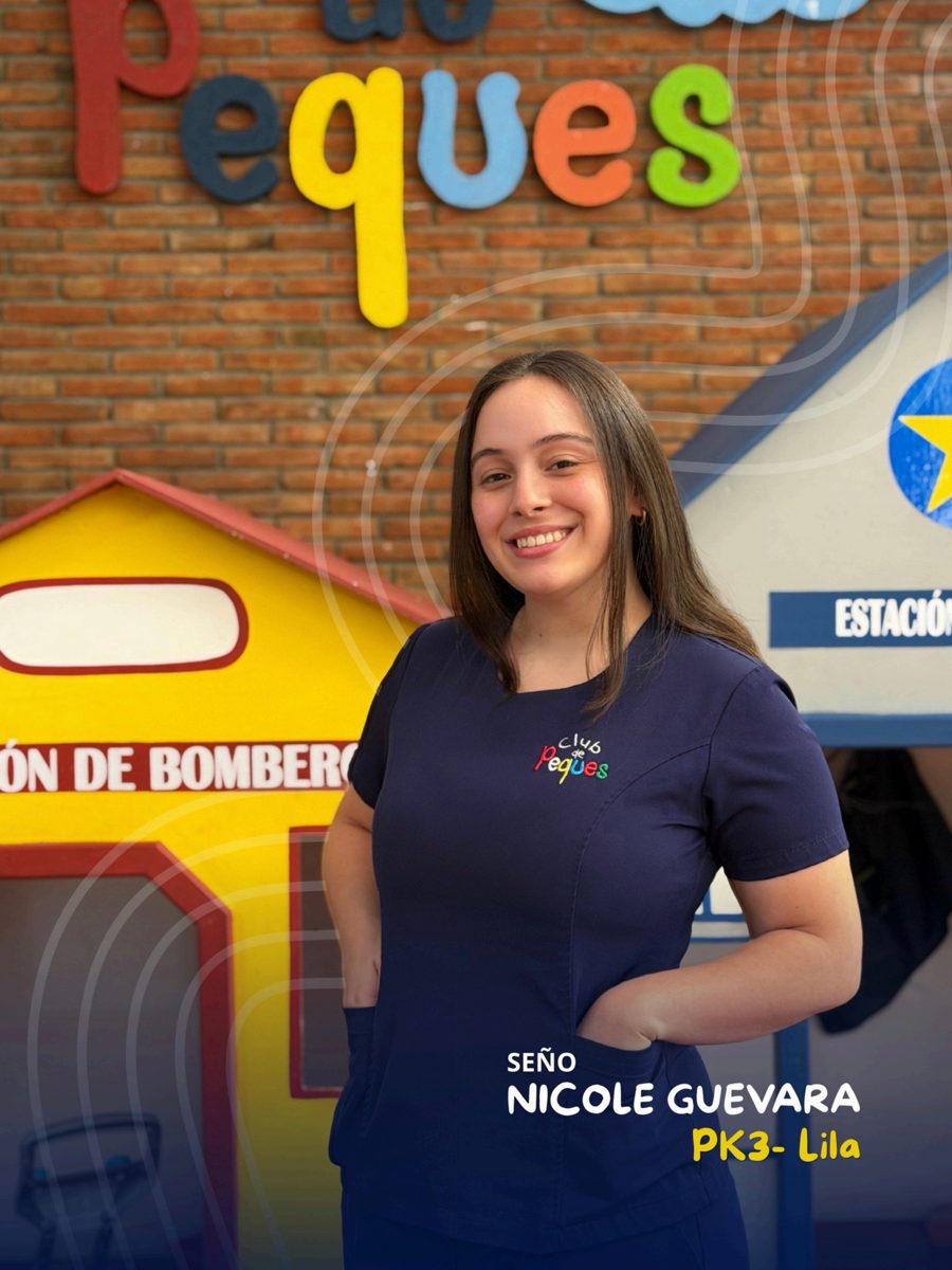 Waist-up portrait of Seño Nicole Guevara smiling, wearing a navy polo, in front of a colorful 'Peques' sign.