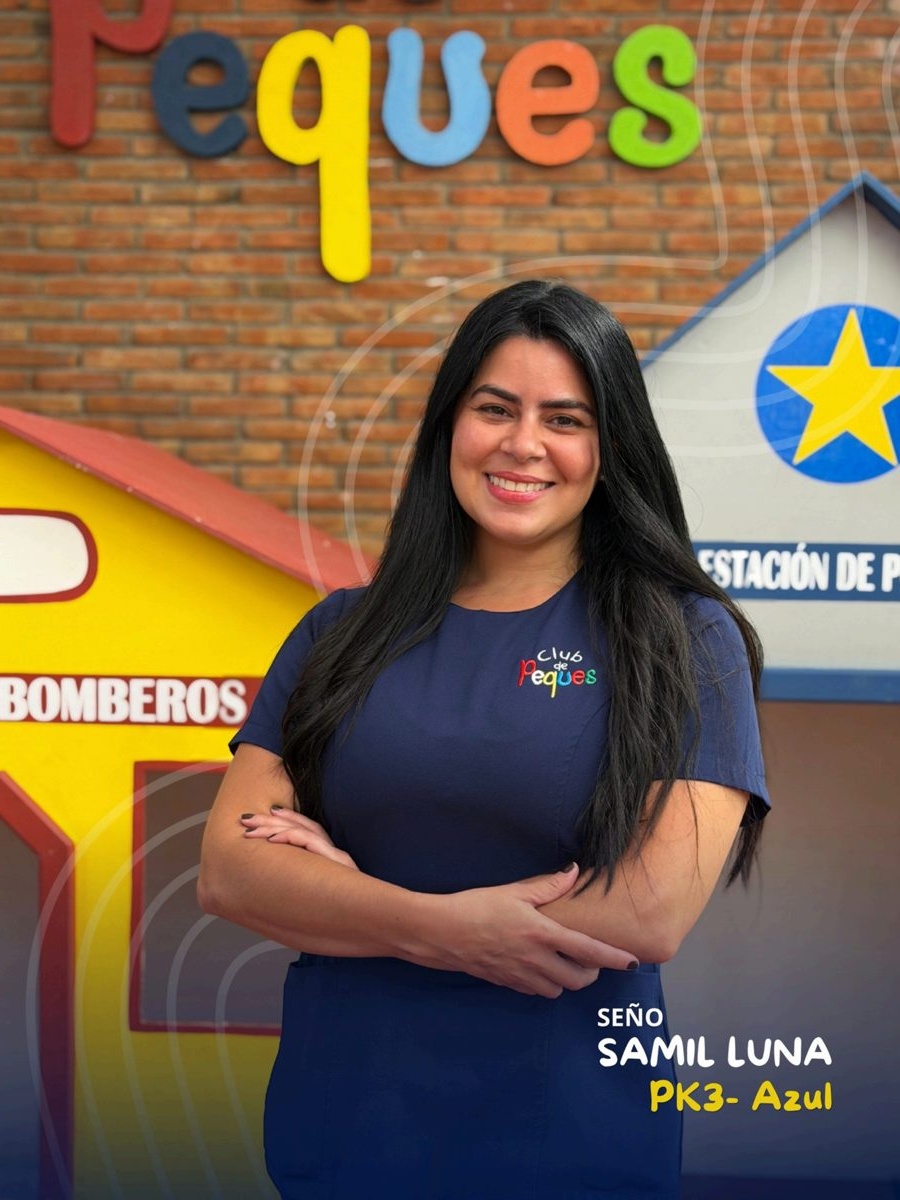 Waist-up portrait of Seño Samil Luna with crossed arms, wearing a navy polo, in front of a colorful 'Peques' sign.