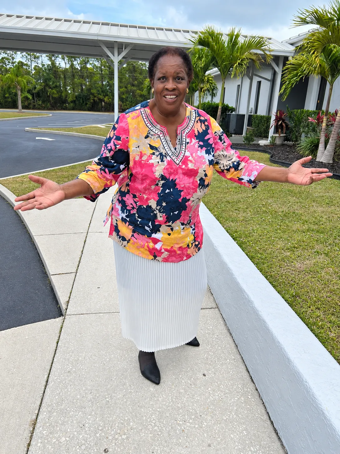 Queen Gladys smiling with her arms open in a warm welcome