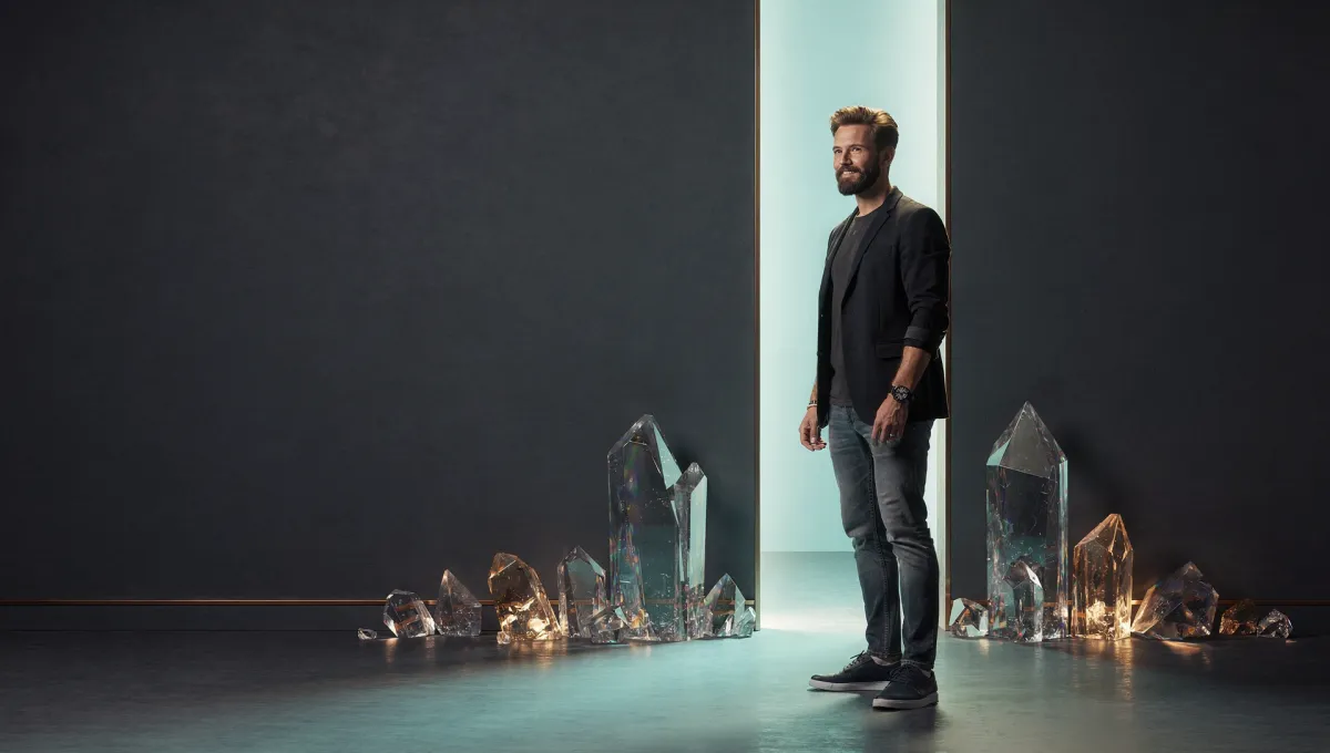 A composed senior leader standing before a tall narrow opening