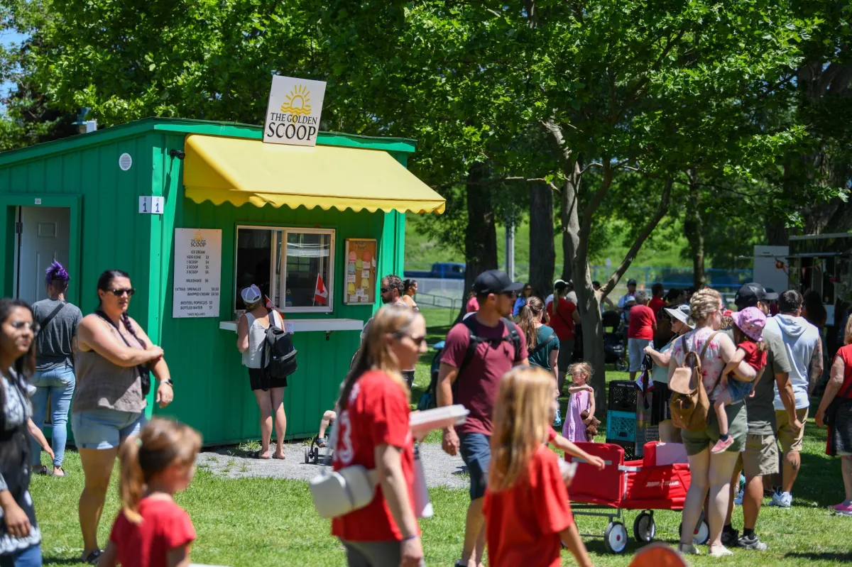 Crowds gathering at Pop-Ups on the Bay as visitors line up for ice cream at The Golden Scoop vendor booth in Belleville’s waterfront park.