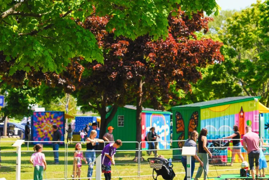 Families and kids walking past artist-painted shipping container stalls at Pop-Ups on the Bay waterfront event in Belleville