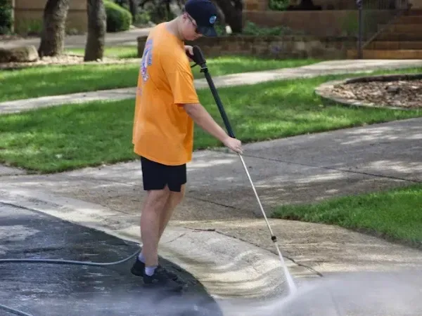 Technician pressure washing a residential driveway