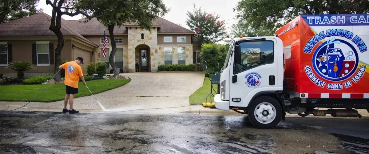Technician pressure washing the street curb in front of a residential home